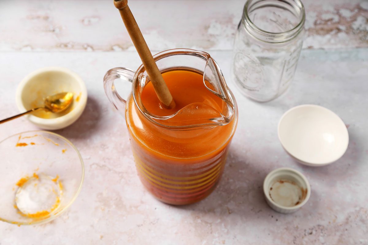 Process of making Taste of Home's Pumpkin Juice in a large pitcher on a grey marble surface.