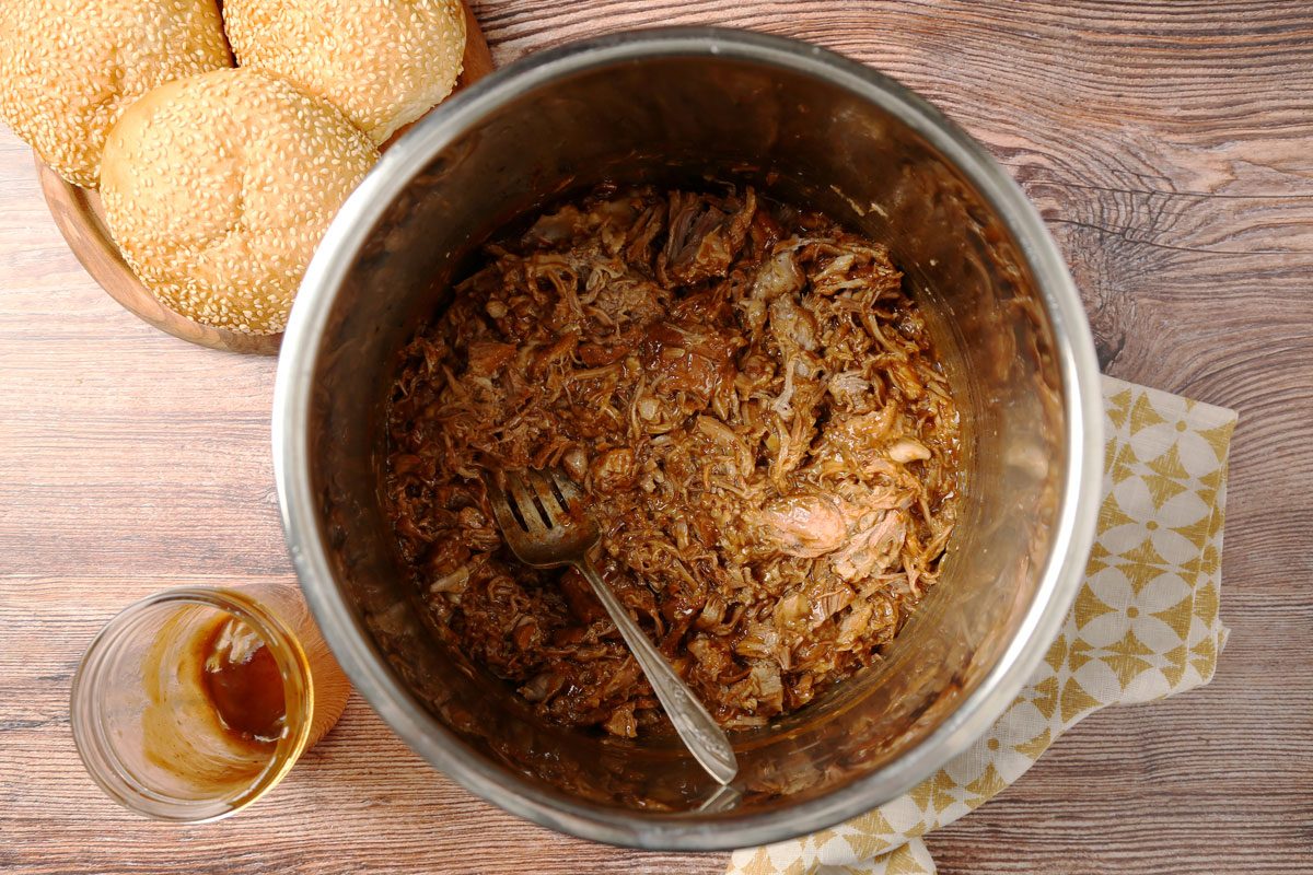 Process of making. Taste of Home's Root Beer Pulled Pork laid out in small bowls on a brown wooden surface.