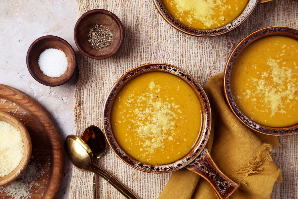 Close up of Taste of Home's butternut squash and sweet potato soup served in brown soup crocks on a brown marble surface.