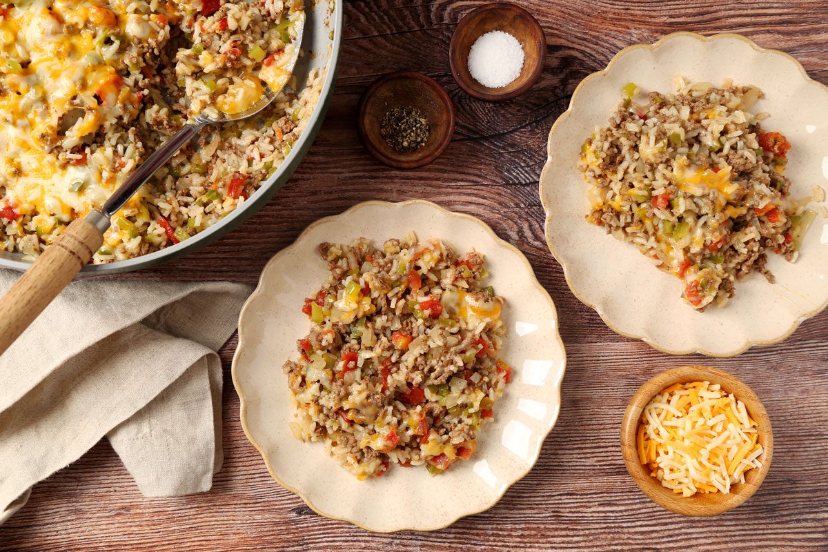 Close up of Taste of Home's Beef and Rice Skillet served on plates on a brown wooden surface.