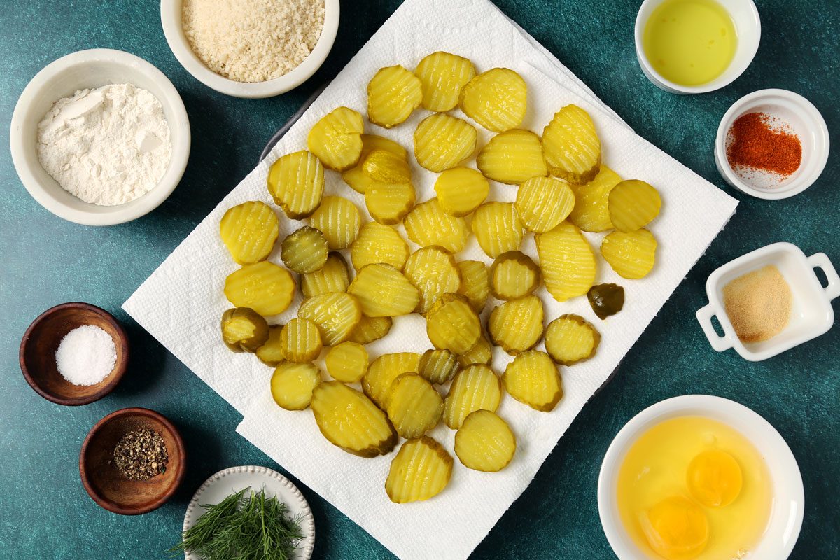 Process of making Taste of Home's Oven Fried Pickles on a wire rack and baking sheet on a teal surface.