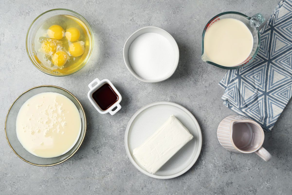 Ingredients for Taste of Home's Flan de Queso laid out in small bowls on a grey marble surface.