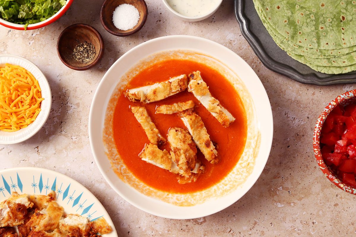 Process of making Taste of Home's Buffalo Chicken Wrap. Chicken being dipped in hot sauce mixed with butter.