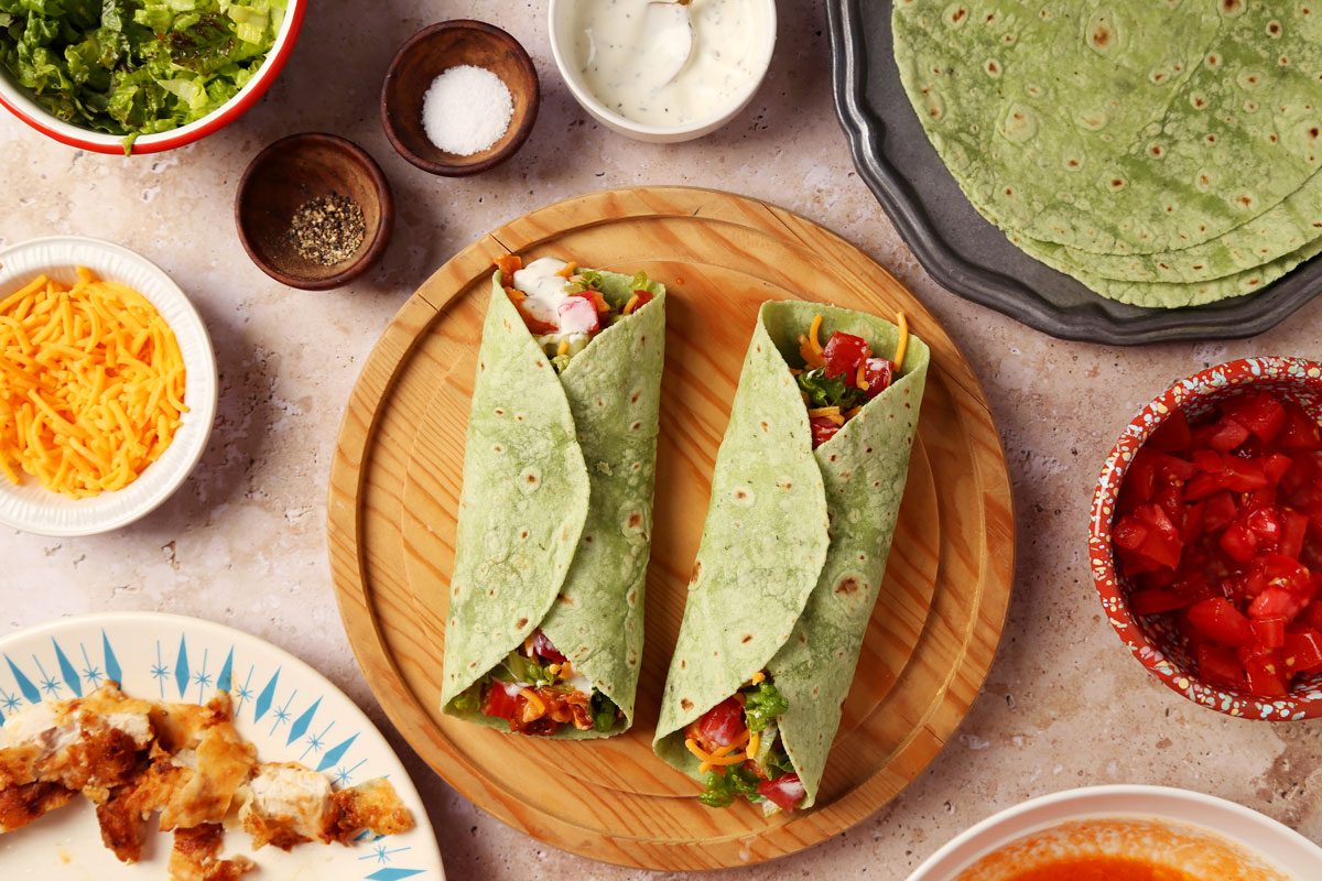 Buffalo Chicken WrapaProcess of making Taste of Home's Buffalo Chicken Wrap on a wooden serving platter on a beige surface.