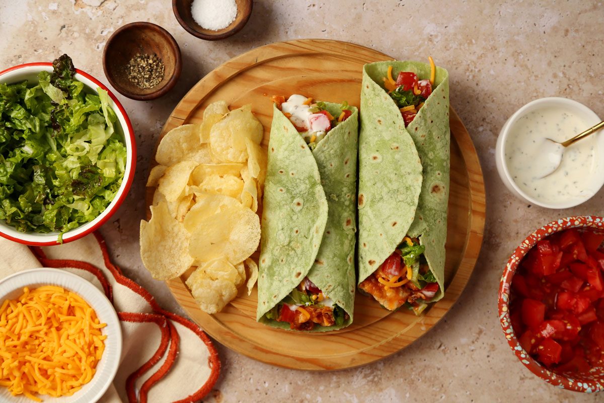 Close up of Taste of Home's Buffalo Chicken Wrap on a wooden serving platter on a beige surface.