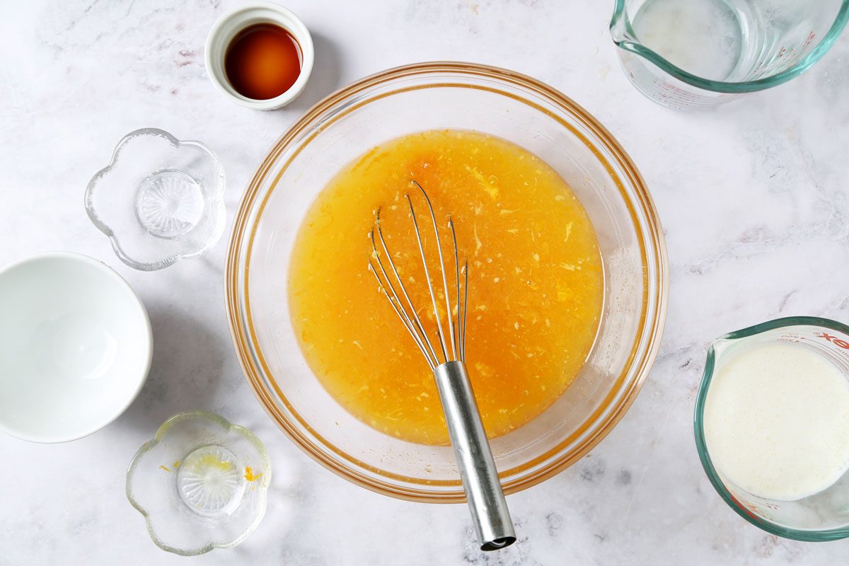 Process of making Taste of Home's Orange Sherbet in a large mixing bowl on a white marble surface with an orange towel.