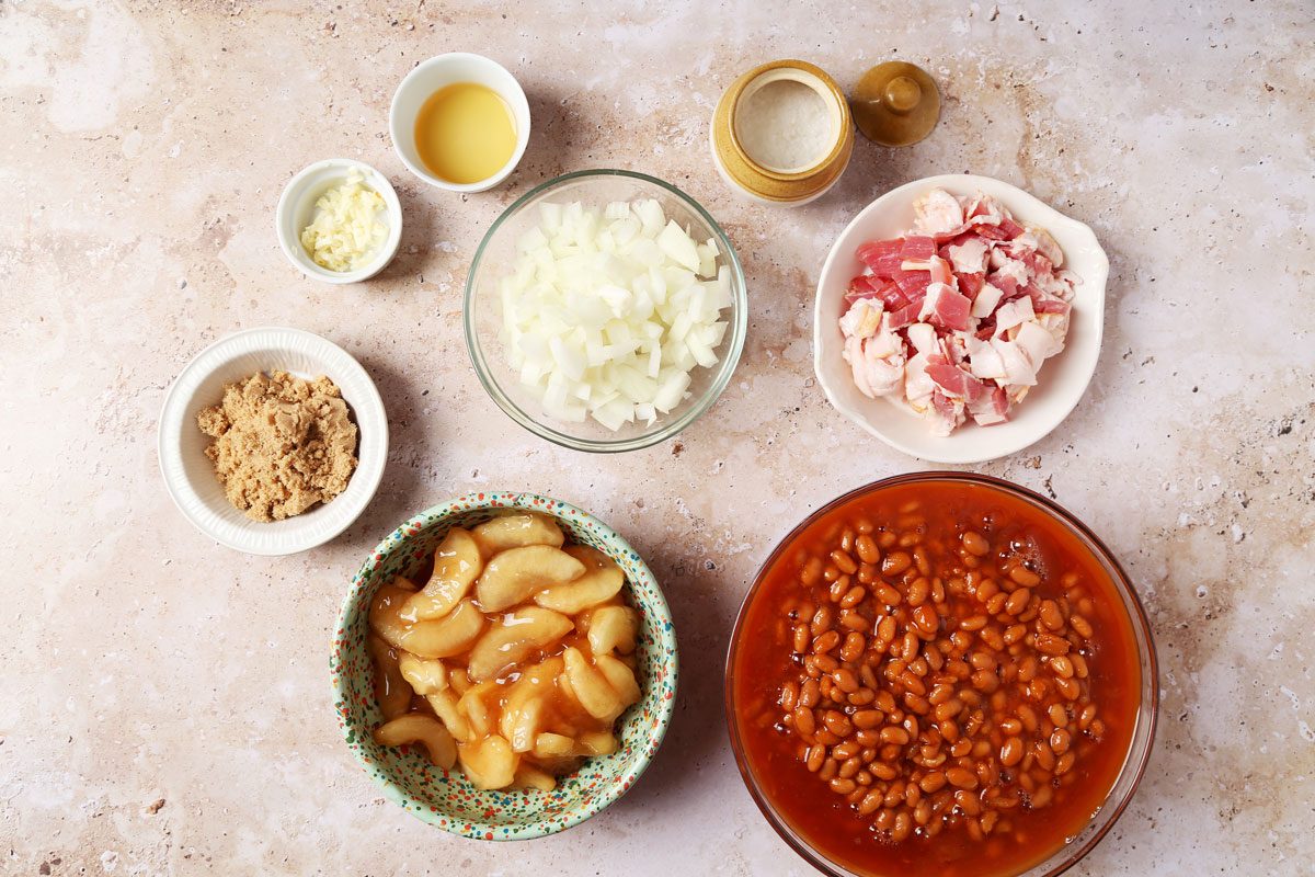 Ingredients for Taste of Home's Apple Pie Baked Beams laid out in small bowls on a brown marble surface.