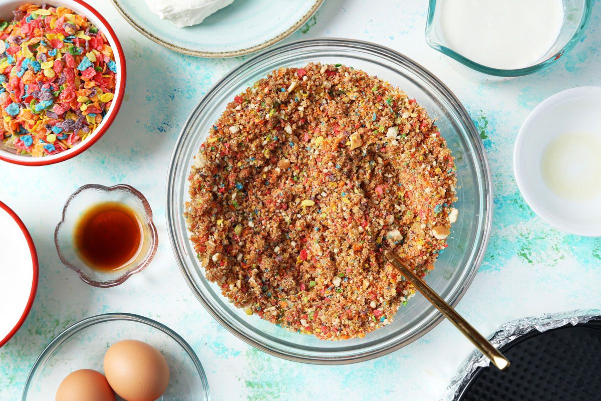 Process of making Taste of Home's Fruity Pebbles Cheesecake crust being made in a large bowl.