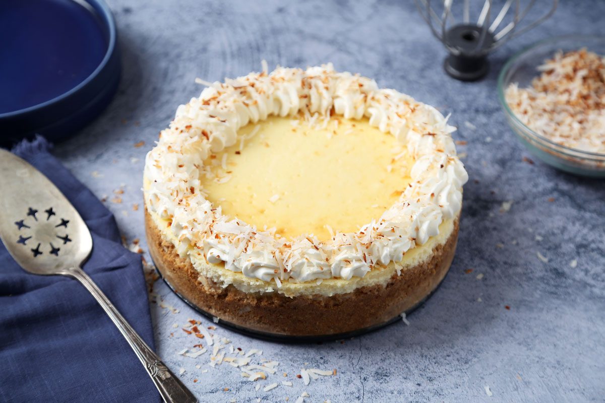 Close up of Taste of Home's Coconut Cheesecake served on blue plates on a dark blue surface.