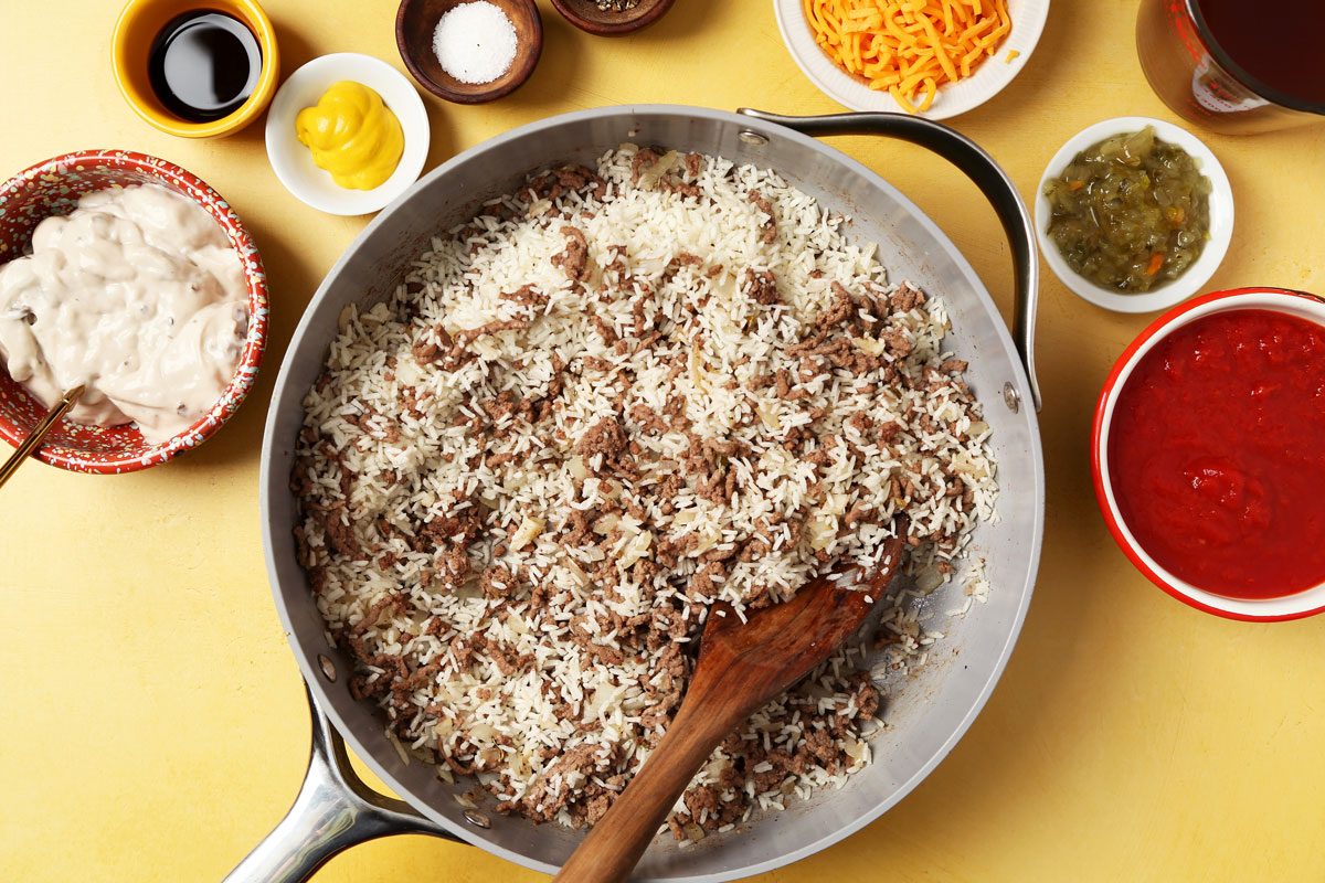 Process of making Taste of Home's Hamburger Casserole in a large nonstick skillet on a bright yellow surface.
