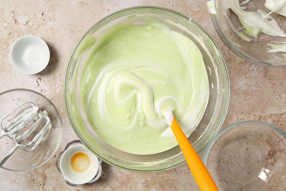Process of making Taste of Home's Pandan Cake making the cake batter in a large mixing bowl on a brown marble surface.