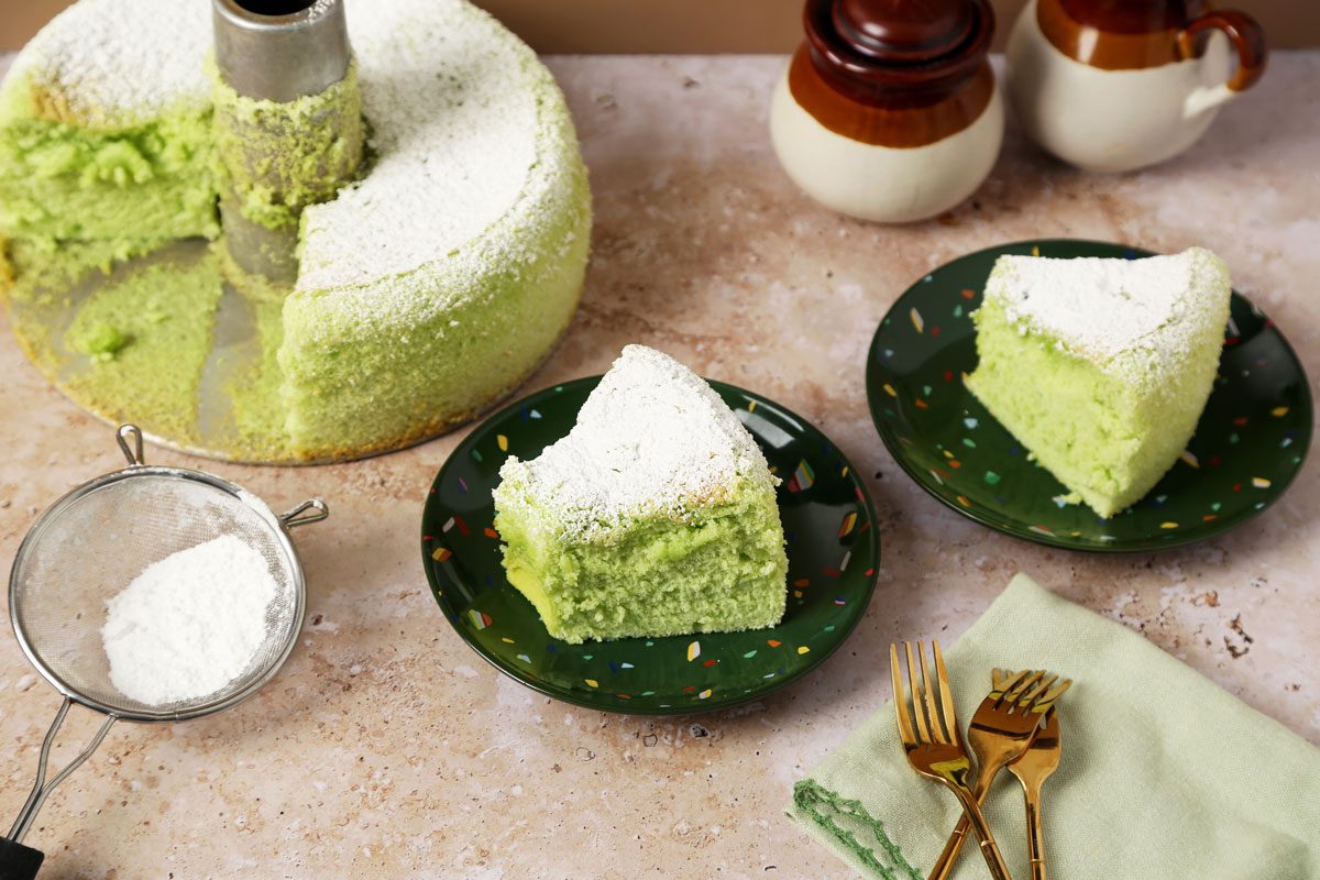Close up of Taste of Home's Pandan Cake sliced and served on green plates on a brown marble surface.
