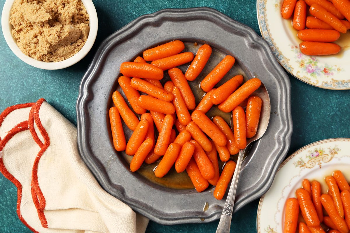 Close up of Taste of Home's Glazed Carrots served on a large dish with a green surface.