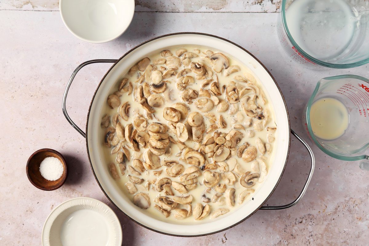 Process of making Taste of Home's Creamed Mushrooms in a large pot on a grey surface.