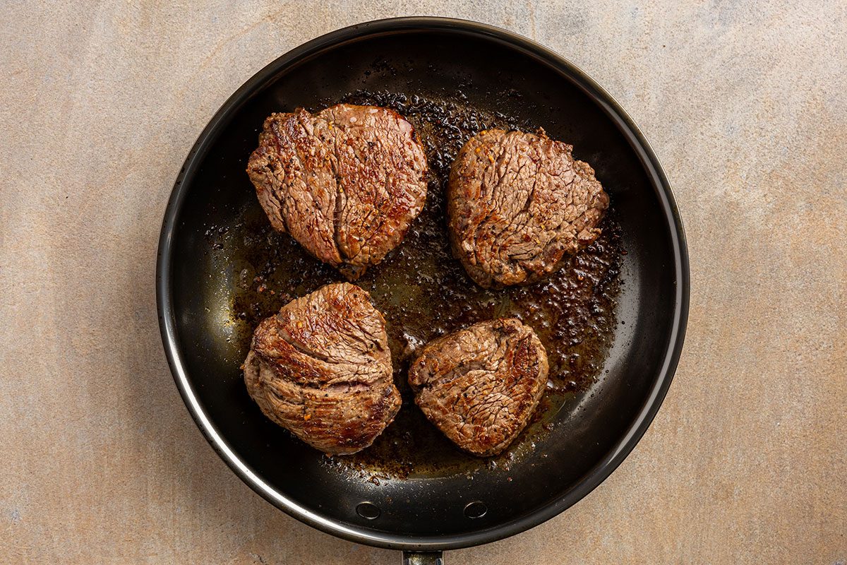 steaks cooking in skillet