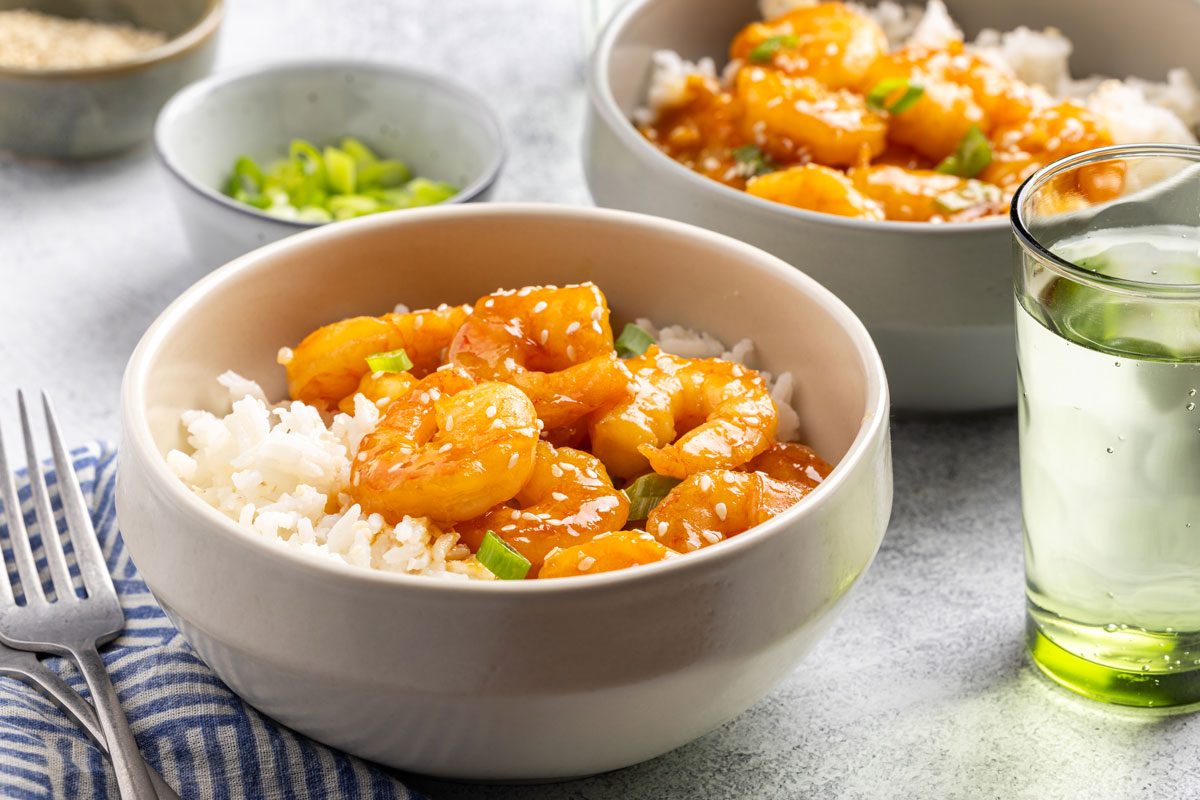 Teriyaki Shrimp portioned into bowls with rice, green onions and sesame seeds as garnish.