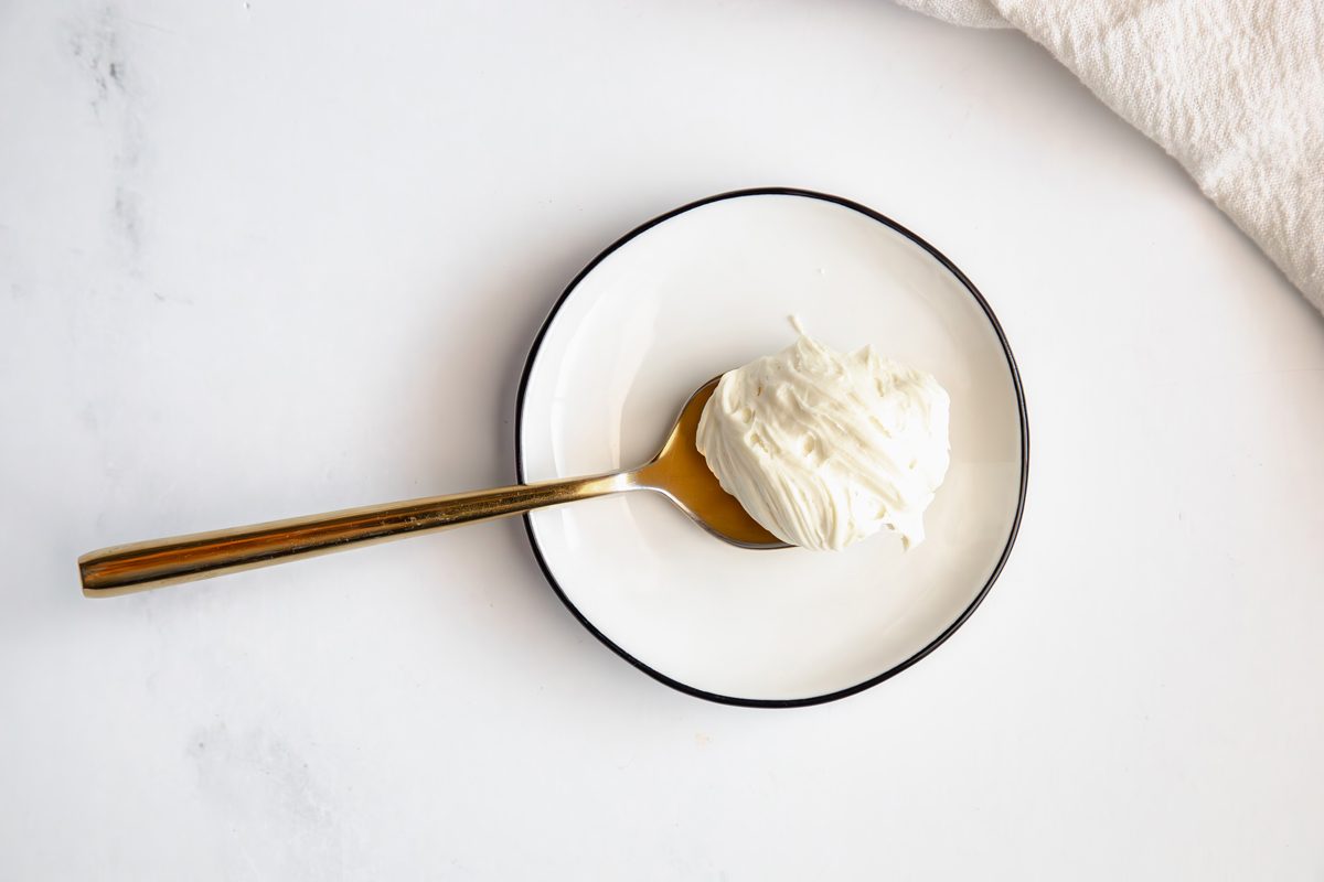Close up shot for Taste of Home White Chocolate Ganache, ganache on a golden spoon on a plate.