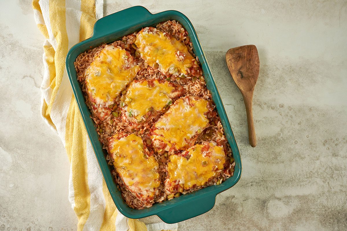 Overhead hero shot of the finished Taste of Home Arroz con Pollo, showcasing the golden melted cheese over the baked chicken and rice, served in a baking dish.