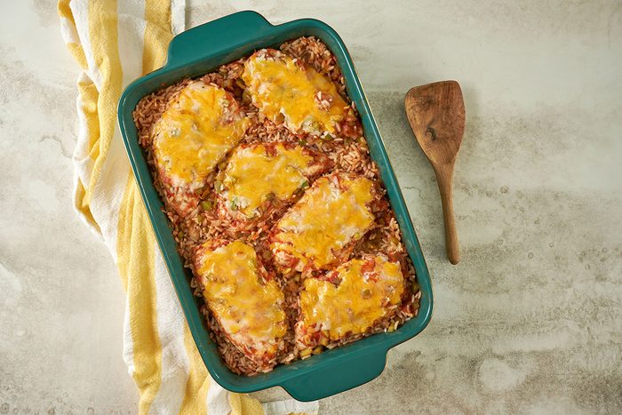 Overhead hero shot of the finished Taste of Home Arroz con Pollo, showcasing the golden melted cheese over the baked chicken and rice, served in a baking dish.