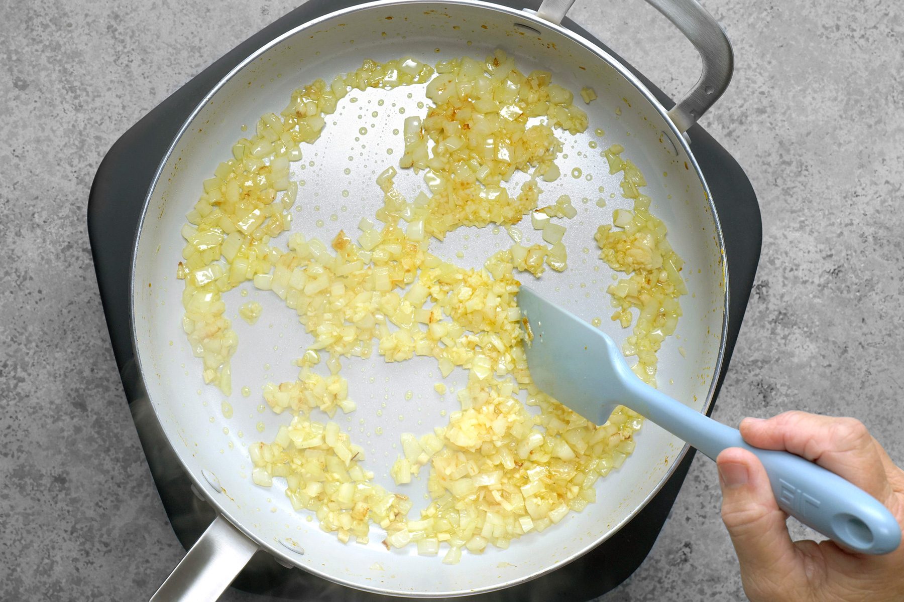 Sliced onions are being sautéed in a skillet, turning golden and translucent as they cook.