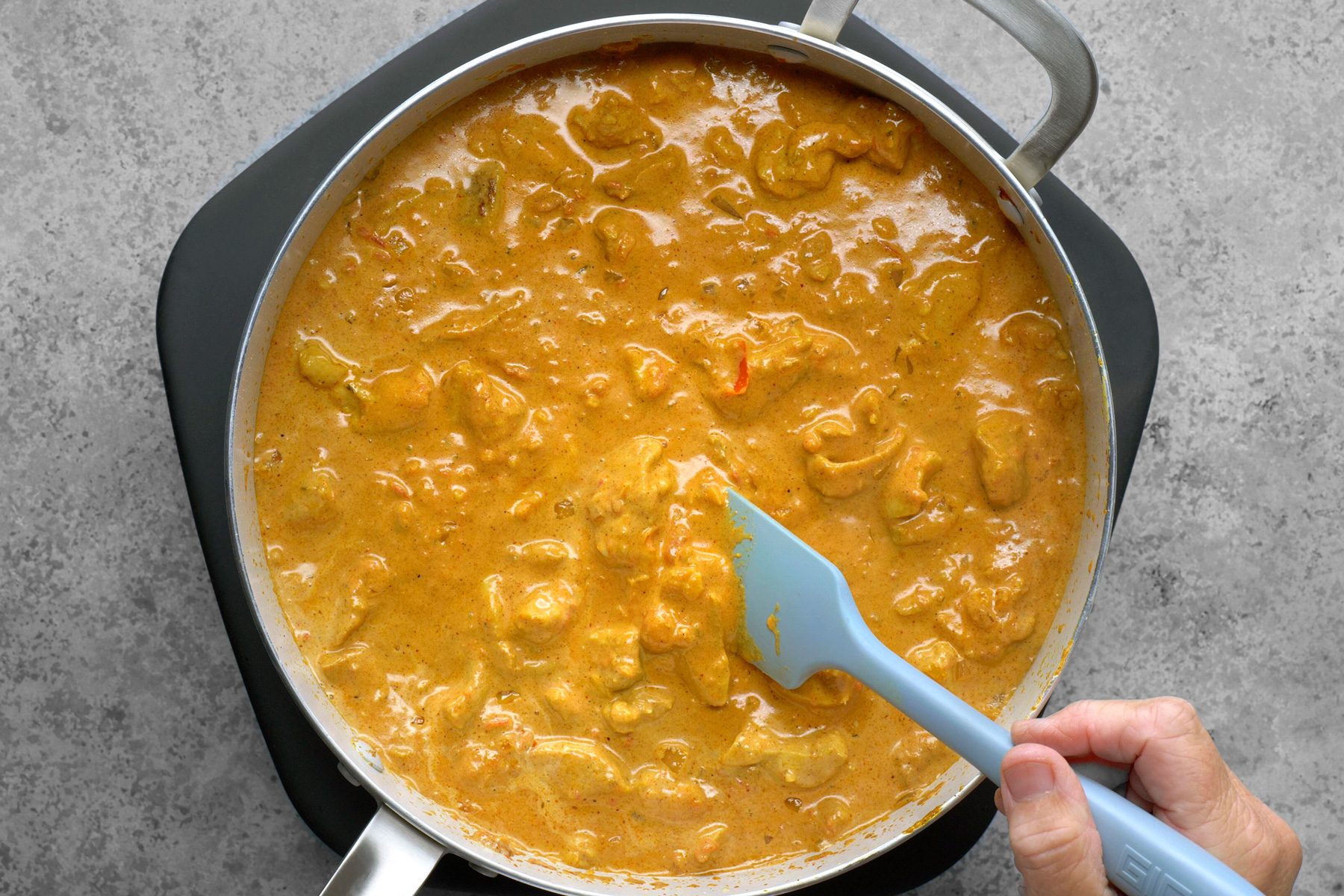 Chicken pieces are boiling in the same skillet, absorbing the flavors of the sauce as they cook. The bubbling liquid creates a fragrant aroma, while the chicken gradually transforms, becoming tender and infused with the rich, savory blend of spices and ingredients.