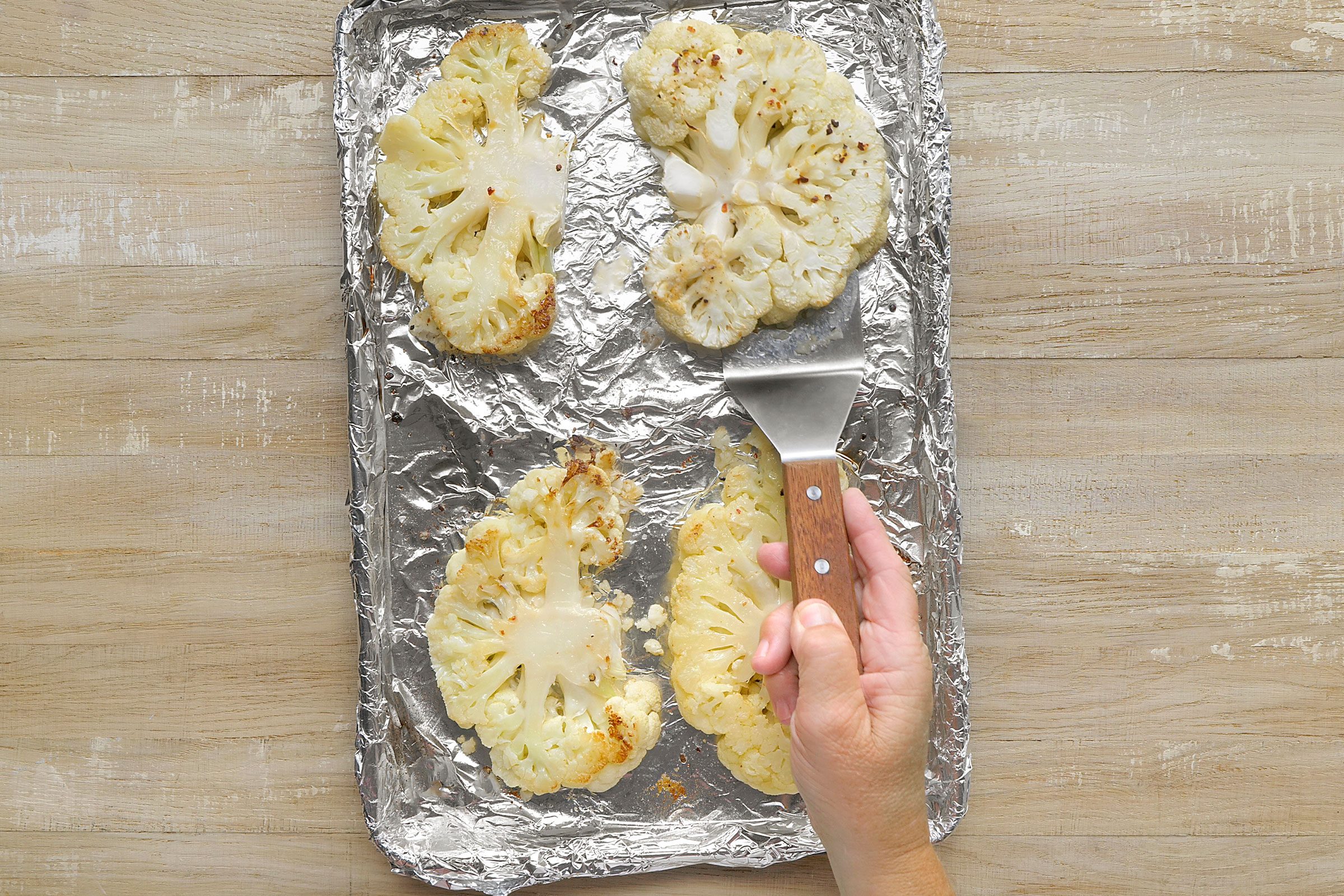 Flipping around the lightly brown roasted cauliflower slices
