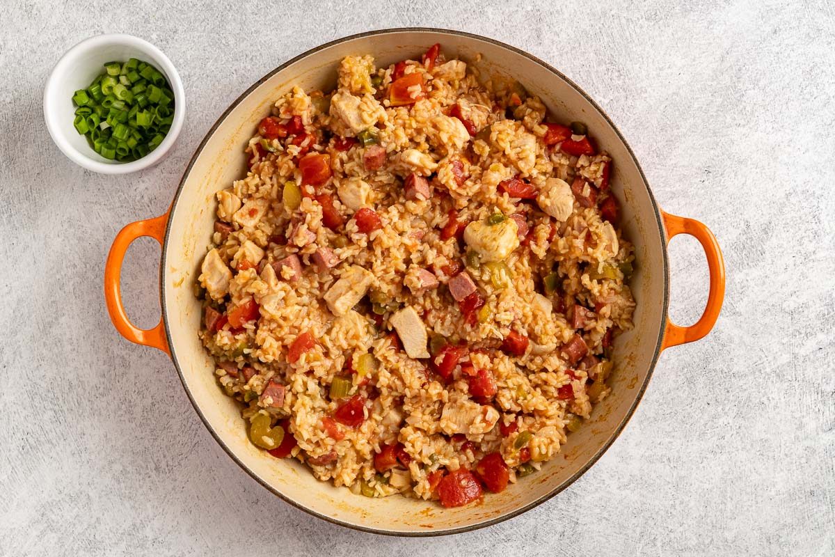 Taste of Home Chicken Jambalaya photo of adding the tomatoes with a side of green onions for topping.