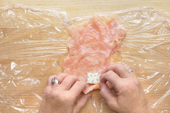 Placing butter cube on beaten chicken breast