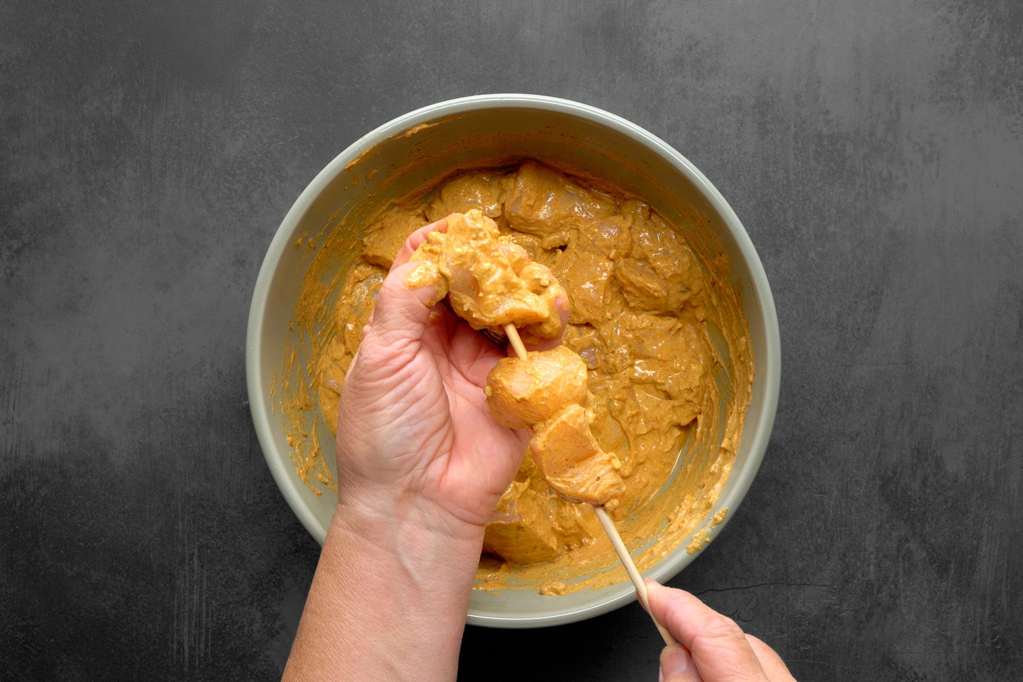 Using wooden skewer to thread the marinated chicken pieces