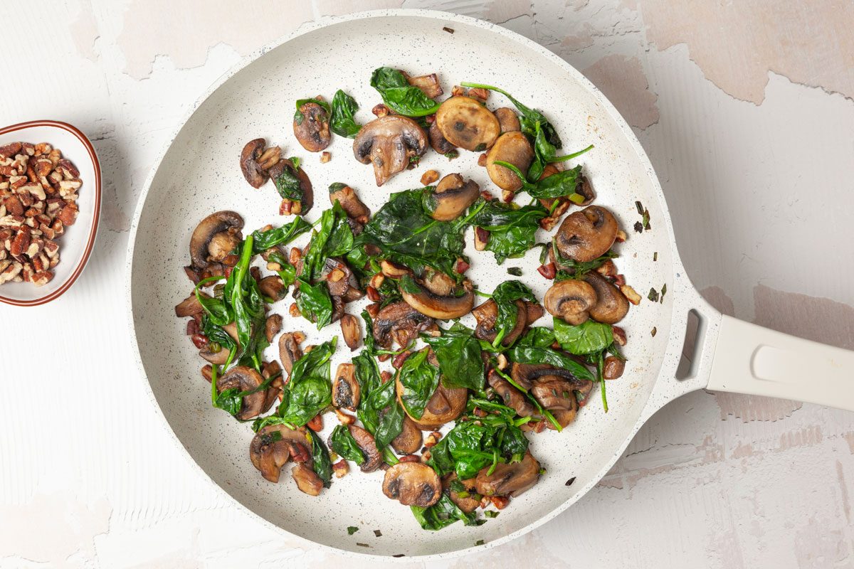 Step 1 of Taste of Home Chicken with Spinach and Mushrooms is to saute the mushrooms, spinach, pecans