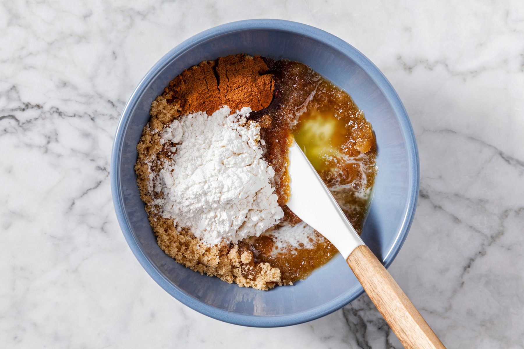 Overhead shot of mixing butter, brown sugar, cinnamon, and flour in a small bowl until well combined, set aside on a marble surface with a spatula.