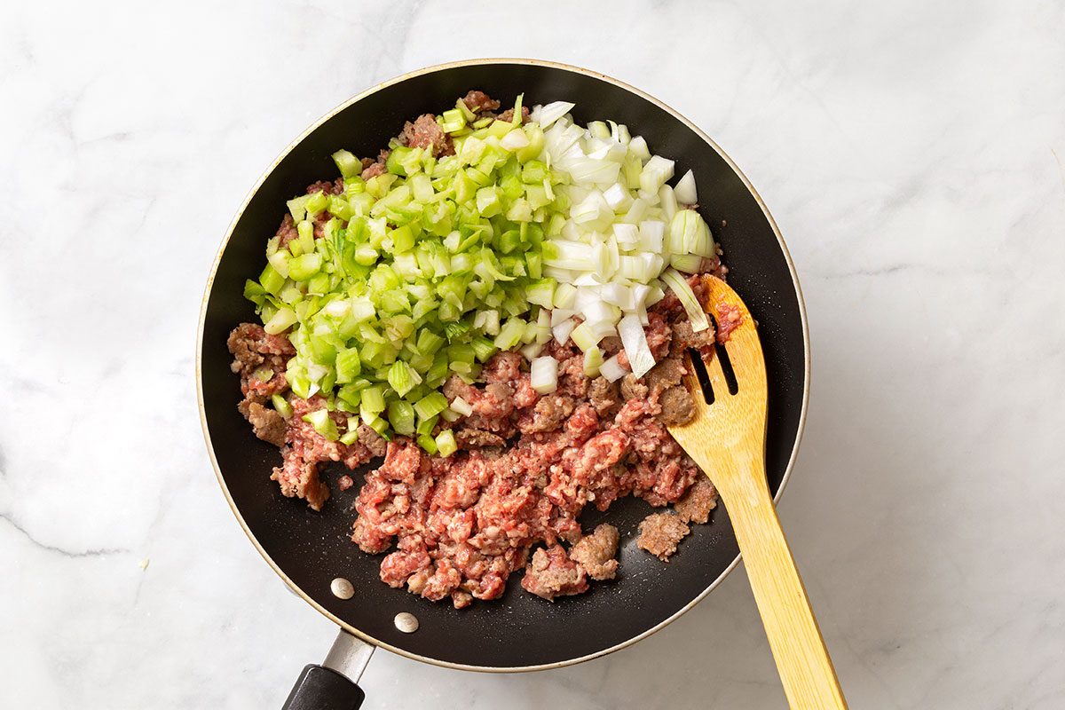 Ground sausage, chopped celery and onion in a large skillet for step two of Cornish Game Hens with Wild Rice Stuffing recipe for Taste of Home