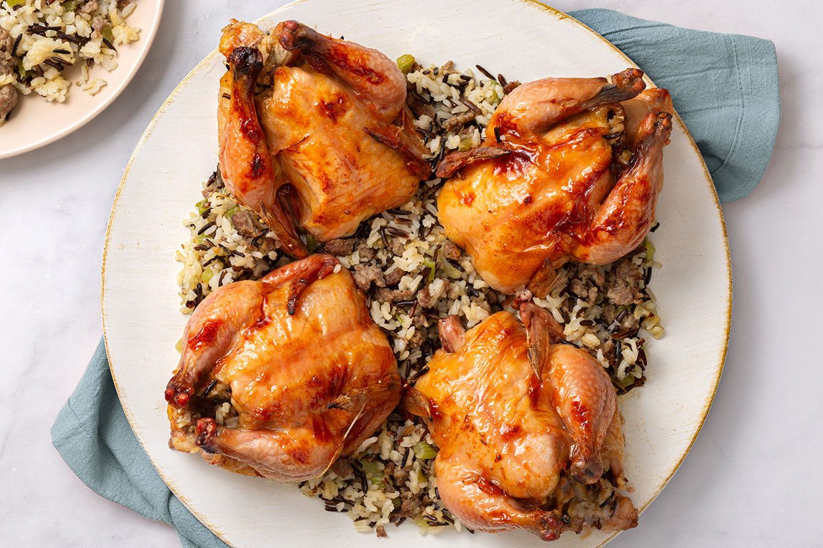 Baked cornish game hens with wild rice stuffing on a serving plate for Taste of Home