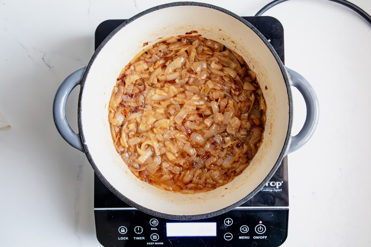 Overhead shot for Taste of Home Creamed Onions, onions in a dutch oven cooking over an induction cooktop.