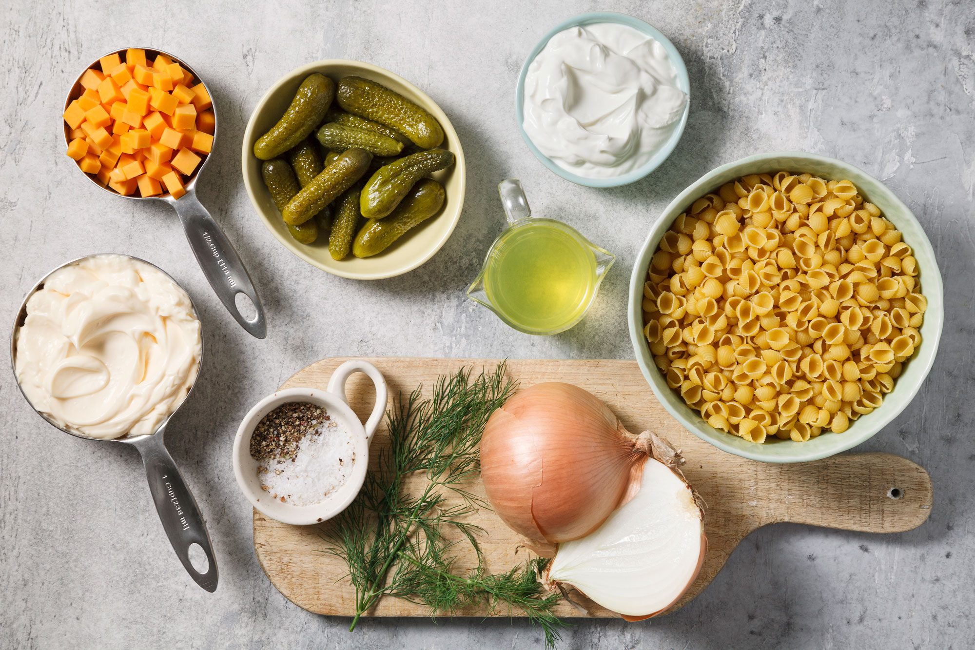 Overhead shot of all ingredients for Dill Pickle Pasta Salad; grey surface;
