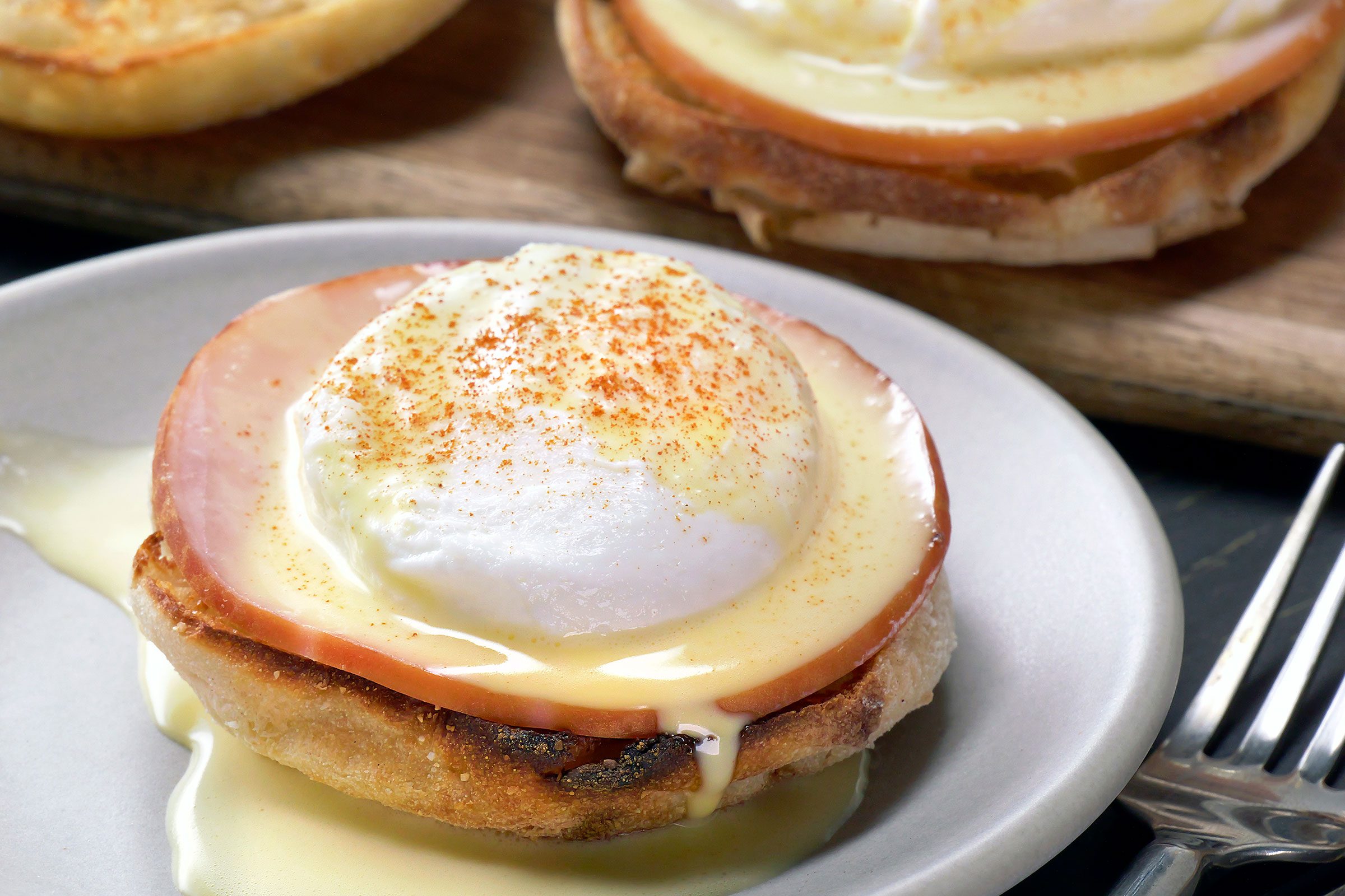 Eggs Benedict served in a white plate with fork on side