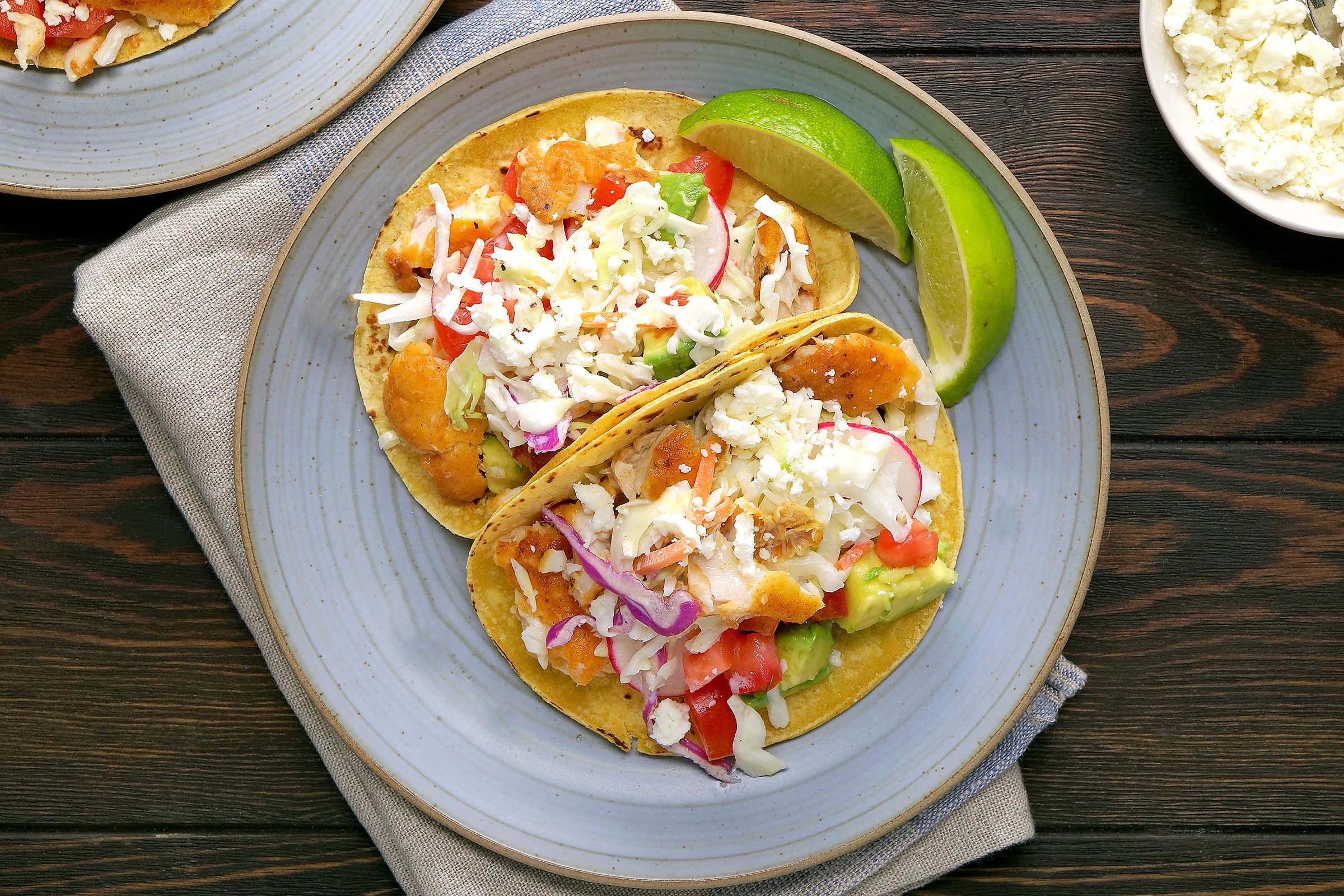 Fish Tacos served in a plate with lemon on side