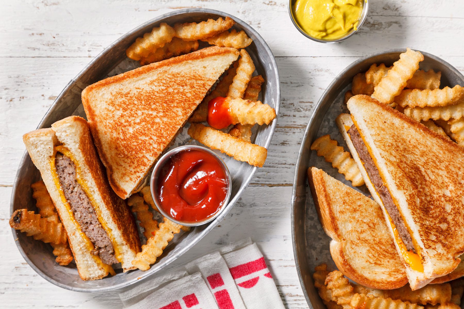 overhead shot of Grilled Cheeseburgers served with mustard and tomato sauce.