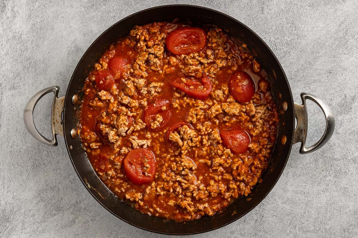 Taste of Home Ground Pork Pasta recipe photo of the tomatoe sauce, stewed tomatoes and Italian seasoning added to the skillet.