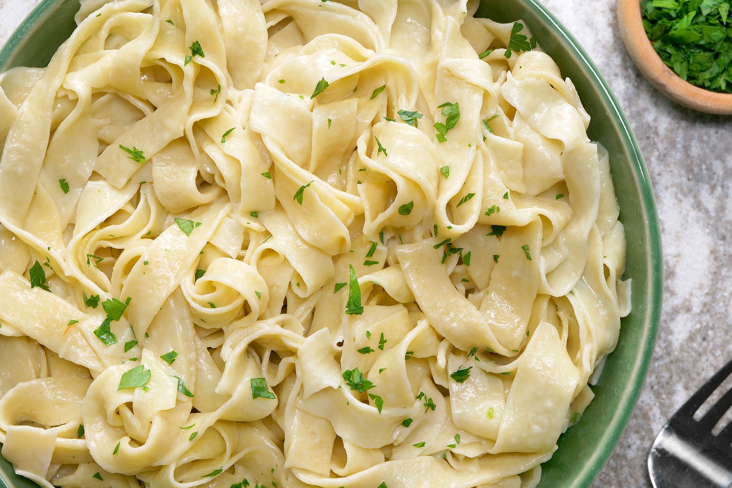 Egg Noodles sprinkled with parsley served in a green bowl