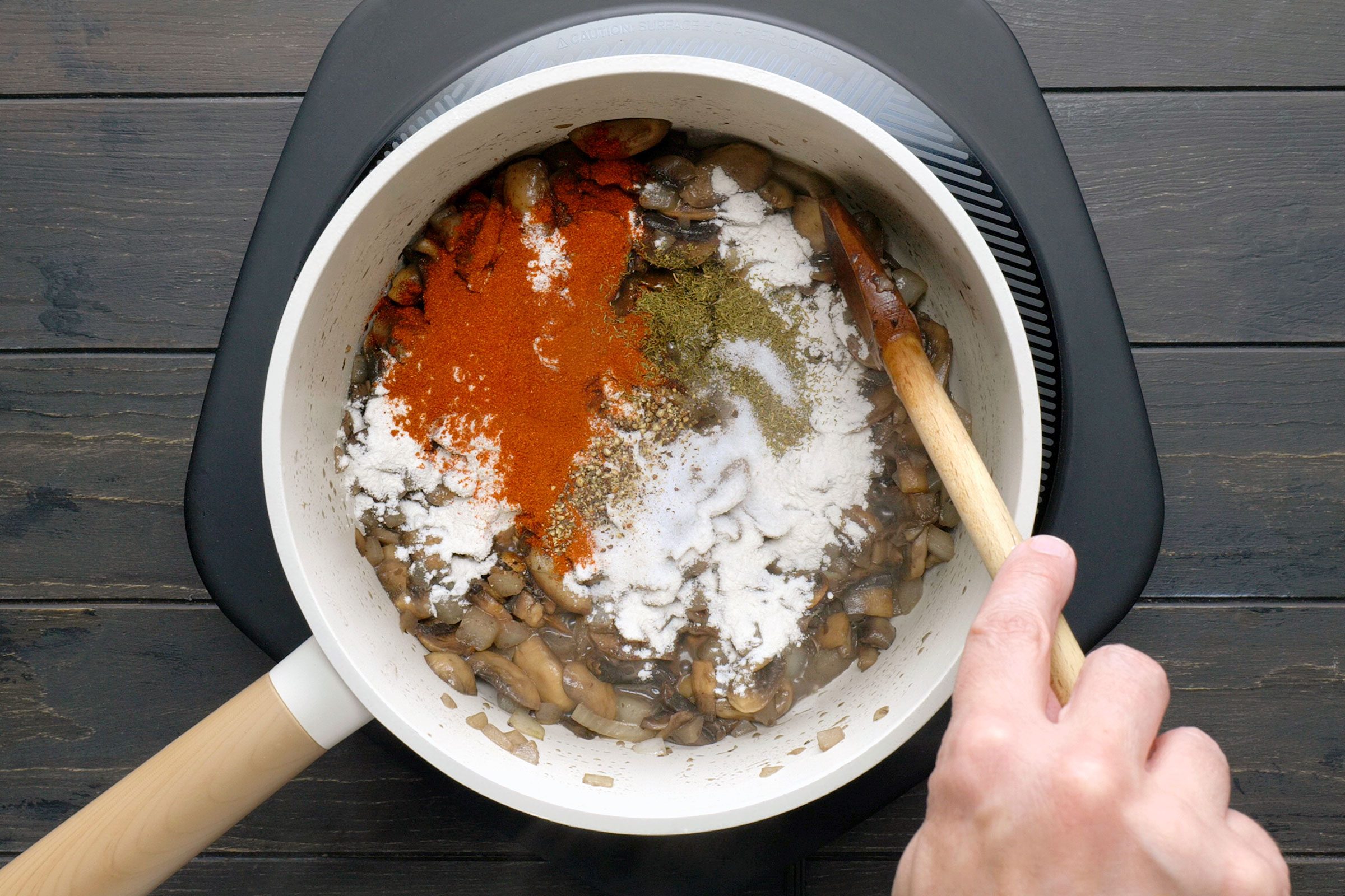 Seasonings and spices sprinkled on mushrooms in a pan