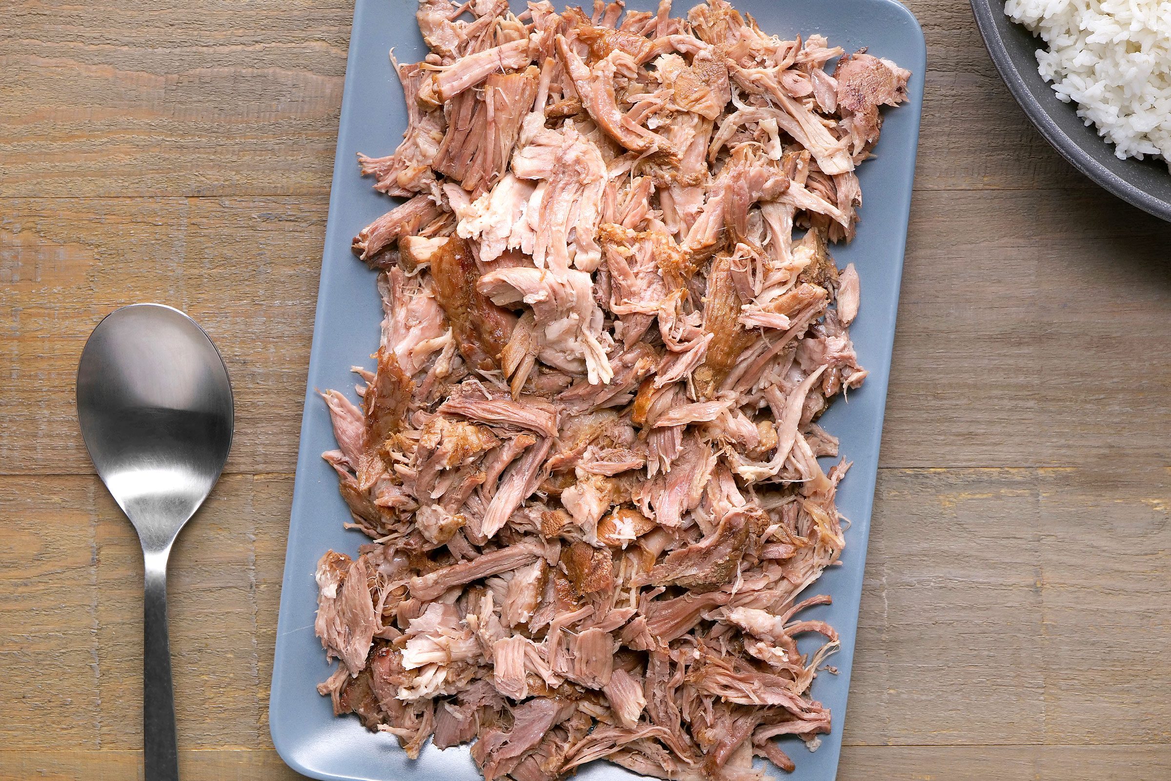 Kalua Pork placed on a dish with a spoon on side