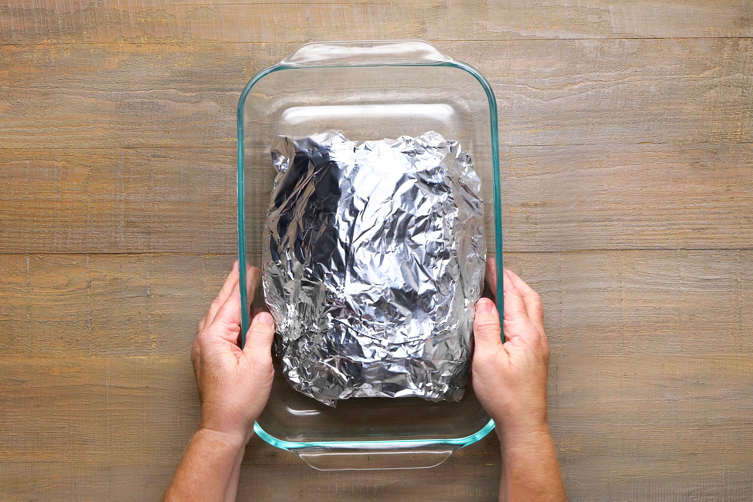 Pork meat wrapped in a foil sheet and placed inside a glass utensil