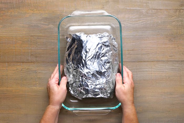 Pork meat wrapped in a foil sheet and placed inside a glass utensil