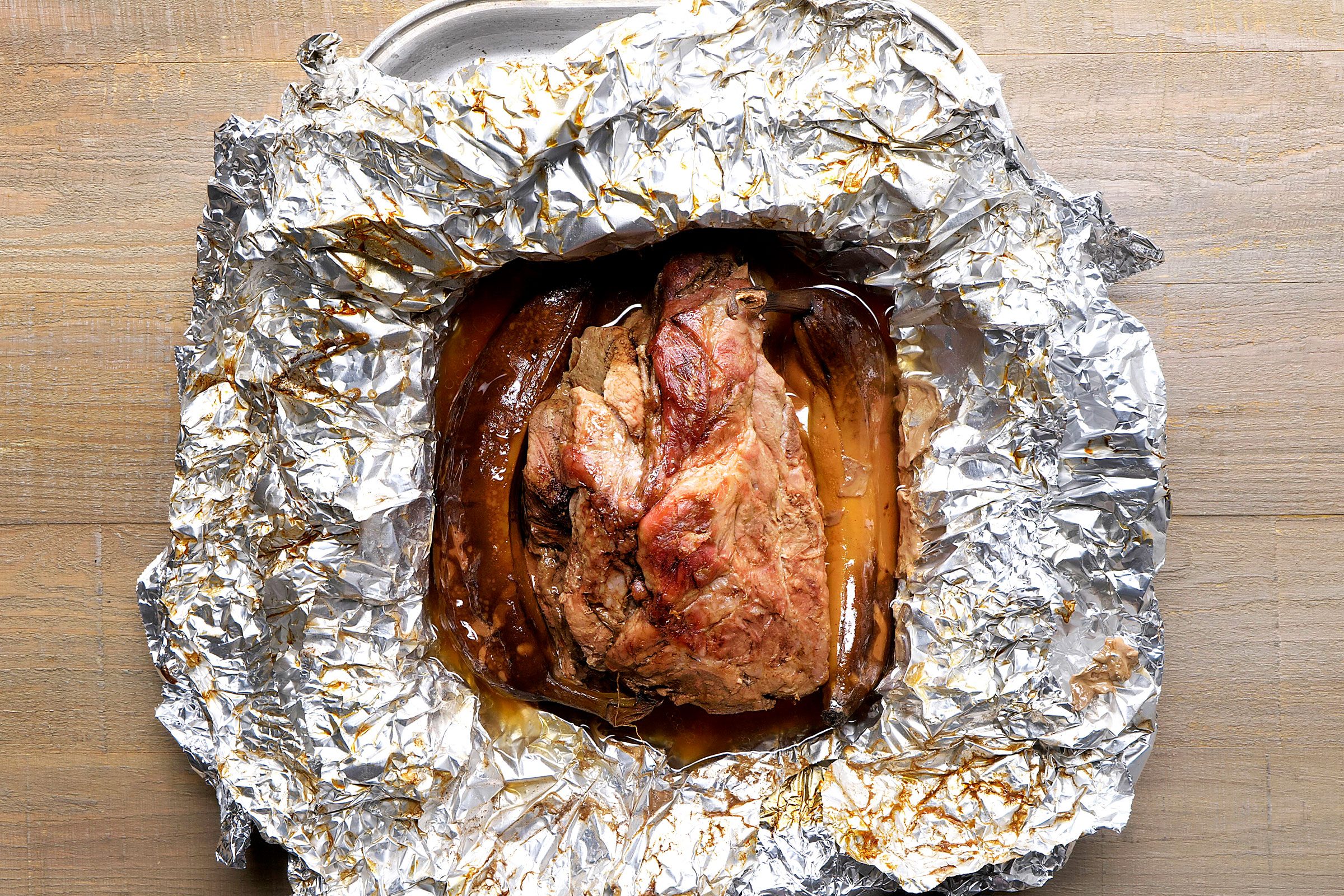 Cooked pork meat and bananas in an opened foil sheet