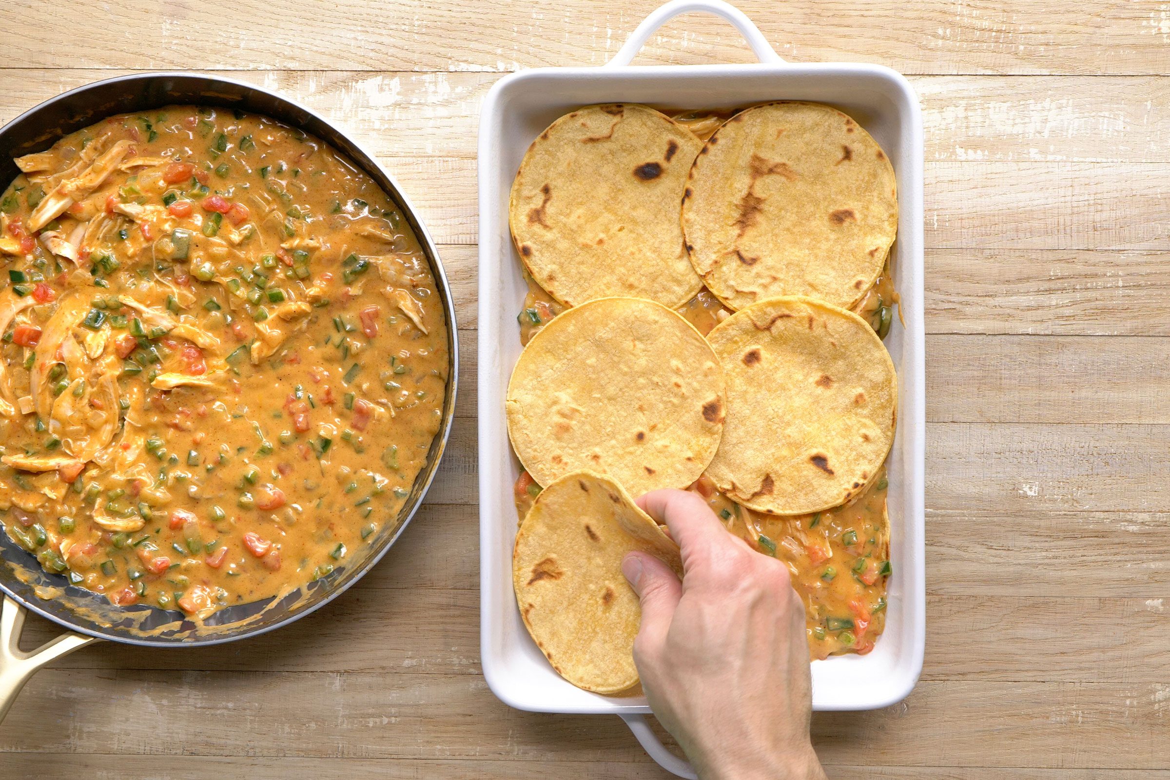 Six tortillas placed in a greased baking dish with chicken mixture on the side