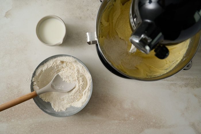 Overhead view of flour, baking powder, and salt being gradually mixed into the creamed butter mixture, alternating with milk, to form the batter for the Taste of Home Lemon Pound Cake recipe.