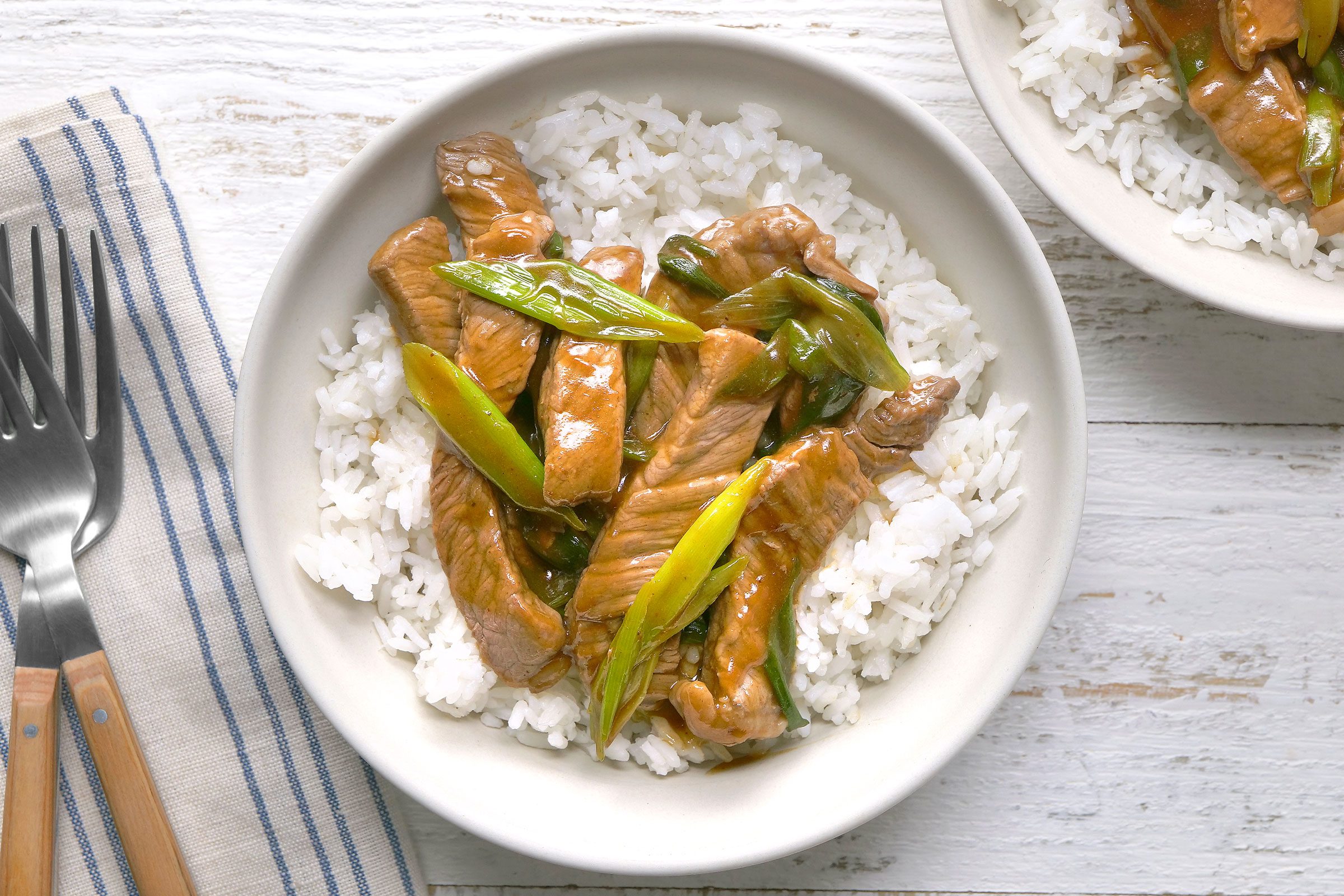 Mongolian Beef served with rice in a white plate with fork placed on side