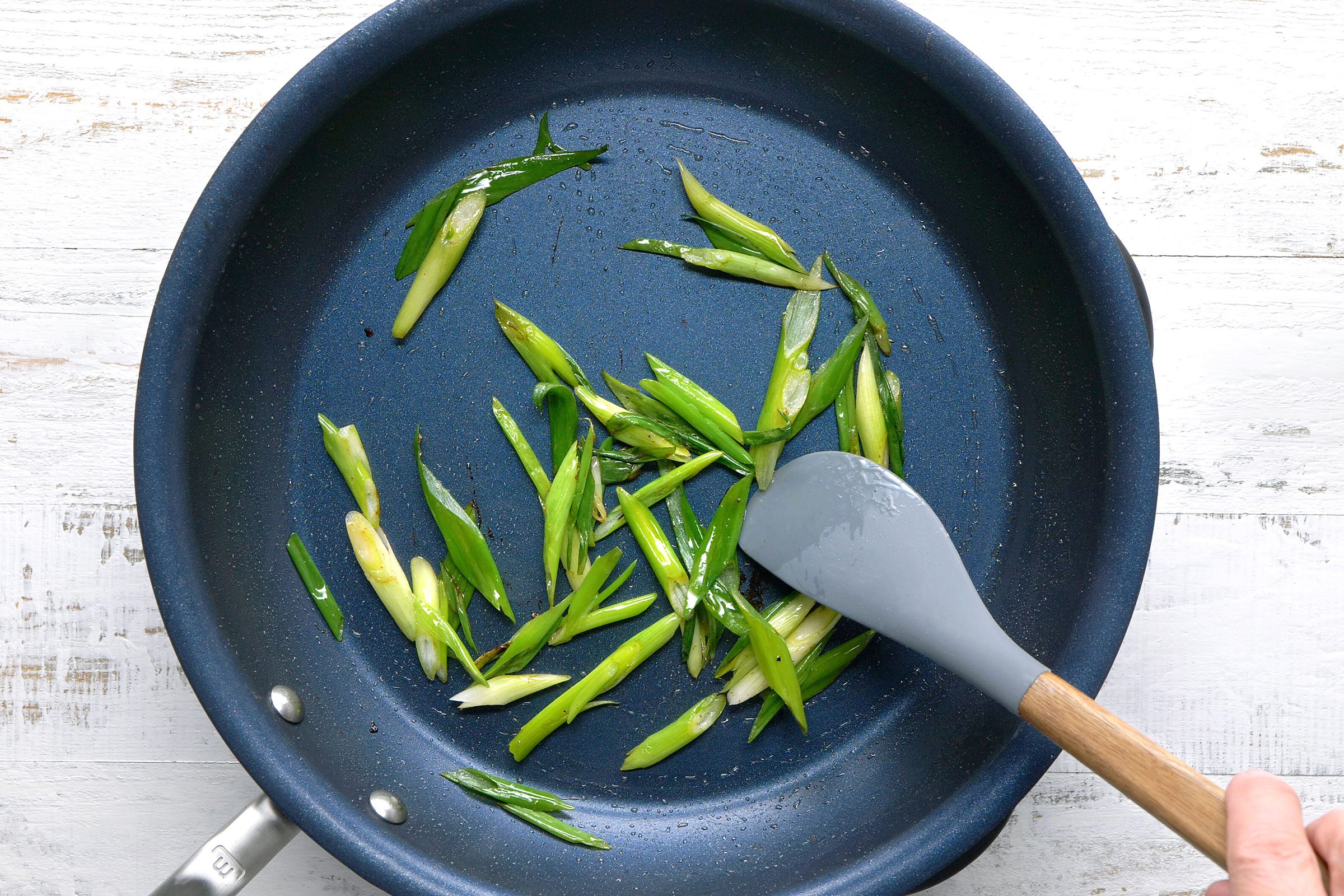 Stir frying green onions in a large skillet