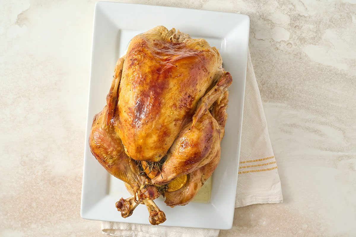 Overhead view of the fully roasted turkey resting on a serving platter after baking, ready for carving for the Taste of Home Champagne and Orange Turkey recipe.